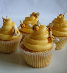 some cupcakes with yellow frosting and bees on top are sitting next to each other