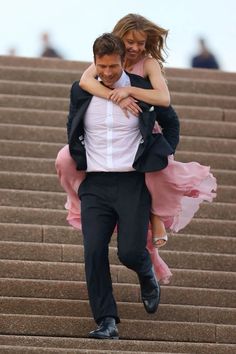 a man in a tuxedo carrying a woman on his back down some steps