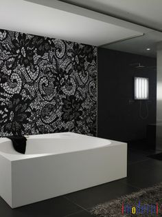 a bath tub sitting on top of a tiled floor next to a wall covered in black and white flowers