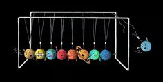 a group of balls with faces on them hanging from a soccer goal in front of a black background