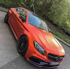 an orange mercedes benz coupe parked on the street