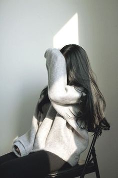 a woman sitting in a chair with her back to the camera and arms behind her head