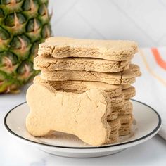 a stack of dog biscuits on a plate next to a pineapple