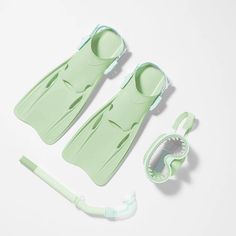 two green plastic baby bath tubs and an infant pacifier on a white surface