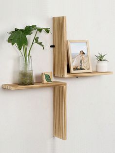 two wooden shelves with plants and pictures on them next to a wall mounted planter