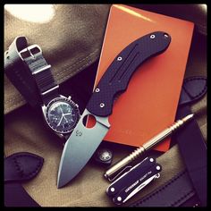 a knife, watch and folder on a backpack