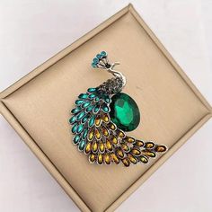 a peacock brooch sitting on top of a box