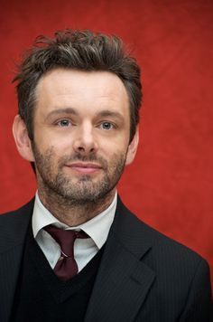 a man wearing a suit and tie in front of a red background