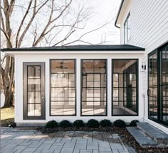 a white house with black windows and brick walkway