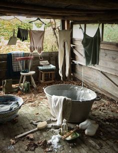 an old bathtub in the middle of a room with clothes hanging from it's ceiling