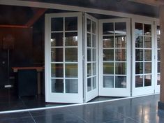 two white double doors open on a black tiled floor outside an office building with large windows