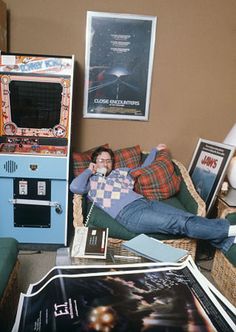 a man laying on top of a couch next to a pile of books and posters