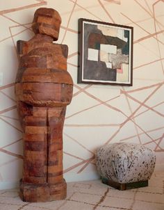 a wooden statue sitting next to a painting on the wall