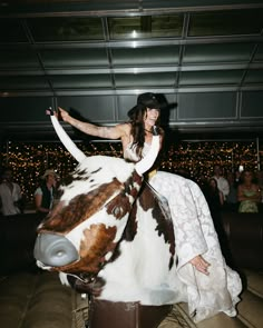 a woman riding on the back of a brown and white horse in a room filled with people