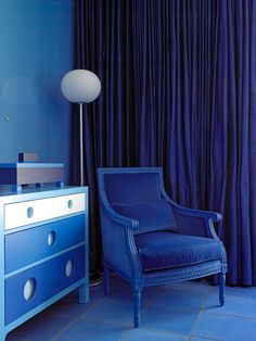 a blue chair sitting in front of a dresser