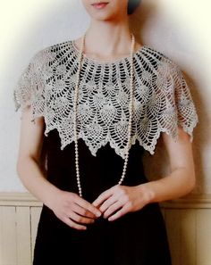 a woman in a black dress is wearing a white crochet top with pearls