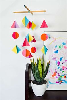 a potted plant sitting on top of a table next to a wall hanging with geometric shapes