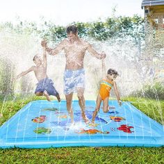 two children and an adult are playing in the sprinkler paddling pool