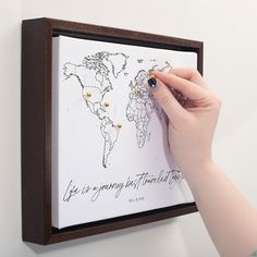 a person is writing on a wall with a world map in the background and gold studs