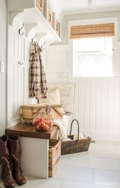 a room with white walls and wooden flooring is decorated with baskets, umbrellas, and other items