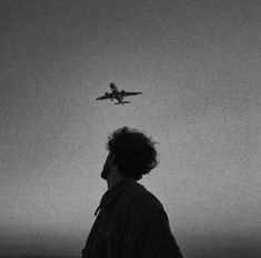 a man looking at an airplane flying over the ocean