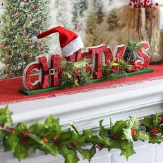 a christmas mantel decorated with holly and red letters