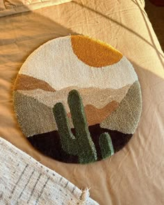 a round rug with a cactus in the middle on top of a bed next to a pillow