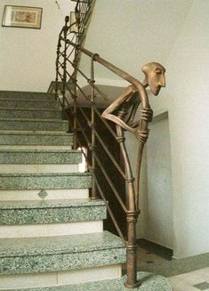 a bronze statue sitting on top of a set of stairs next to a stair case