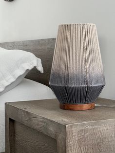 a wooden table with a lamp on top of it next to a pillow and clock