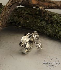 two wedding rings sitting on top of a piece of driftwood next to a tree branch