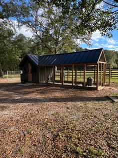 a small shed with a metal roof in the middle of a field next to trees