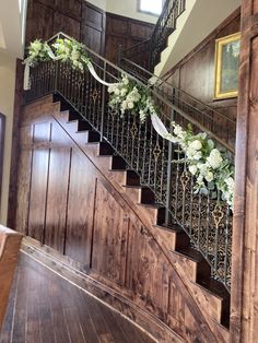 a staircase decorated with flowers and greenery next to a wooden paneled wall in a home