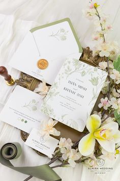 the wedding stationery is laid out on top of some flowers and ribbons, along with other items