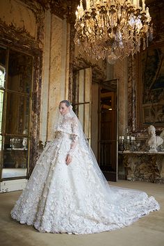 a woman in a wedding dress standing next to a chandelier