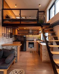 a living room and kitchen with stairs leading up to the top floor in a loft style home