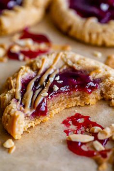 a close up of a cookie with jelly and nuts on the top, next to other cookies