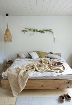 an unmade bed in a bedroom with white walls and wood flooring on the side