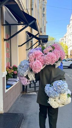 a person walking down the street with flowers on their head and in front of a store