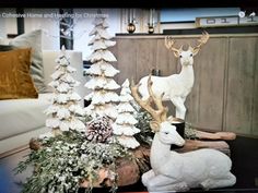 a living room decorated for christmas with white deer and pine trees on the coffee table