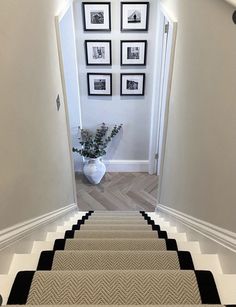 the stairs are lined with black and white chevron rugs, along with pictures on the wall