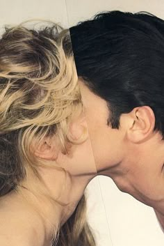 a man and woman kissing each other in front of a white wall with the same image on it