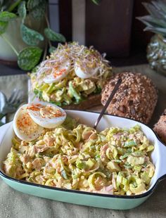 a bowl filled with pasta and an egg on top of it next to some bread