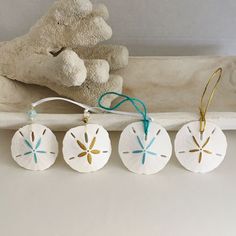 four white sand dollar ornaments are hanging on a shelf next to a teddy bear and stuffed animal