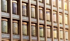 a wall full of jars filled with different types of spices and herbs on display next to each other