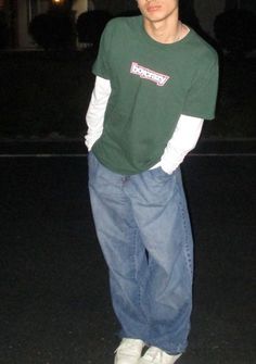 a young man standing in the street at night with his hands on his hips and looking to the side