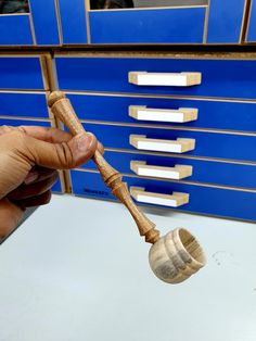 a person holding a wooden spoon in front of a blue drawer with drawers on it