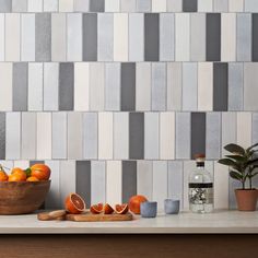 a bowl of oranges sitting on top of a counter next to a cutting board