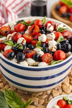 a bowl filled with tomatoes, blueberries and mozzarella on top of a table