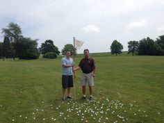 two men are standing in the grass holding hands