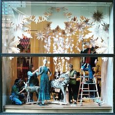 the window display is decorated with snowflakes and mannequins in blue dresses